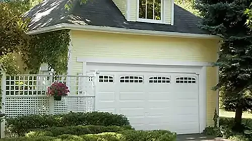 White garage door on a yellow home with a lattice fence